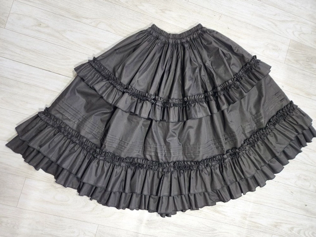 Top-down overhead view of cotton Lolita petticoat laid flat on wooden floor, showcasing full circular A-line silhouette and double ruffle hem construction