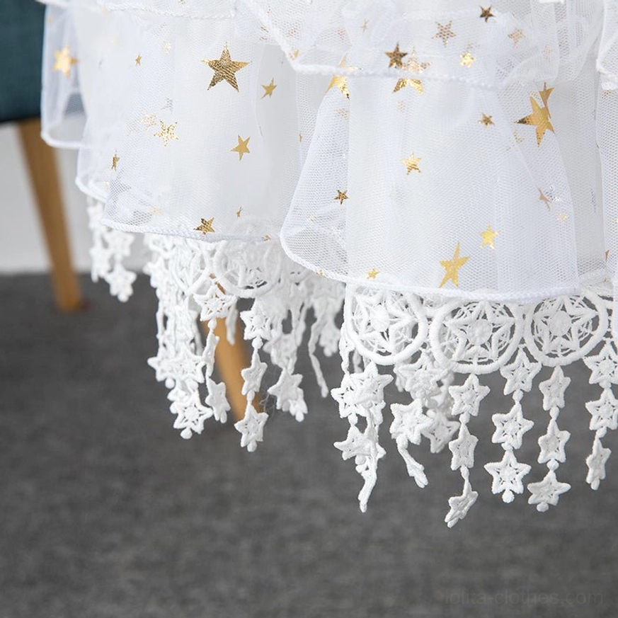 Close-up detail of lolita petticoat white tulle hem with gold star sequins and crochet star-shaped tassel lace trim low-angle studio shot