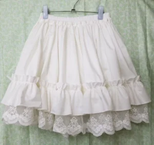 Lolita petticoat hung on metal hanger showing off-white color wide elastic waistband and layered ruffle embroidered lace hem detail