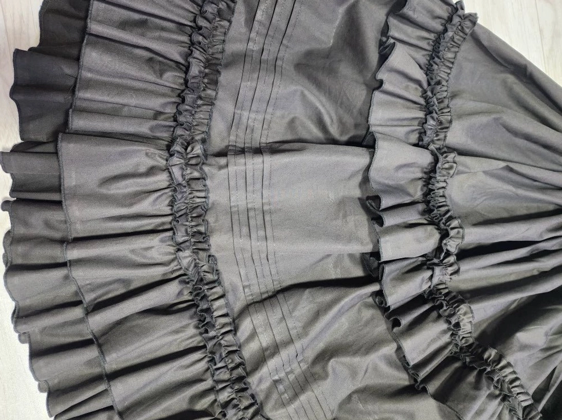 Front close-up view of elasticated waist and upper ruffled skirt area, displaying matte cotton fabric texture and ruffle construction details