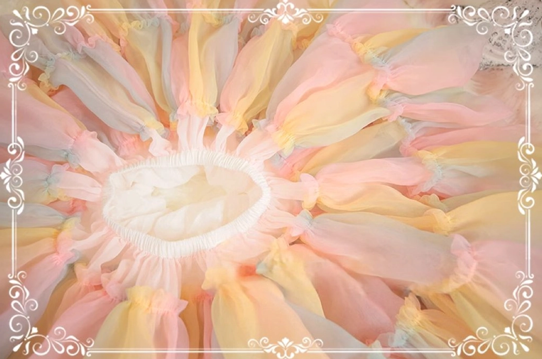 Close-up overhead view of lolita petticoat waist area, focusing on gathered pastel rainbow gradient tulle around central waistband with ornate vintage border
