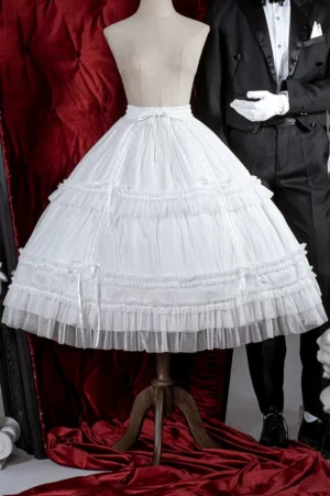 White lolita petticoat with multi-layer tulle ruffles displayed on mannequin with red velvet backdrop, showing drawstring waist and satin ribbon trims