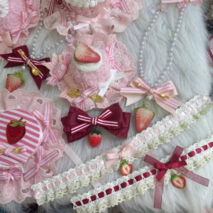 Top-down arrangement of pink and burgundy Lolita matching accessory set with pearl chains, strawberry pendants, striped bows, mini dessert-style hair hats and delicate lace trims on white fur cloth