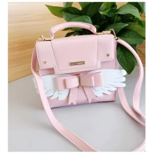 Sweet Lolita pink crossbody bag with detachable strap and white wings bow ornament, three-quarter overhead view showcasing top handles and metal brand plaque