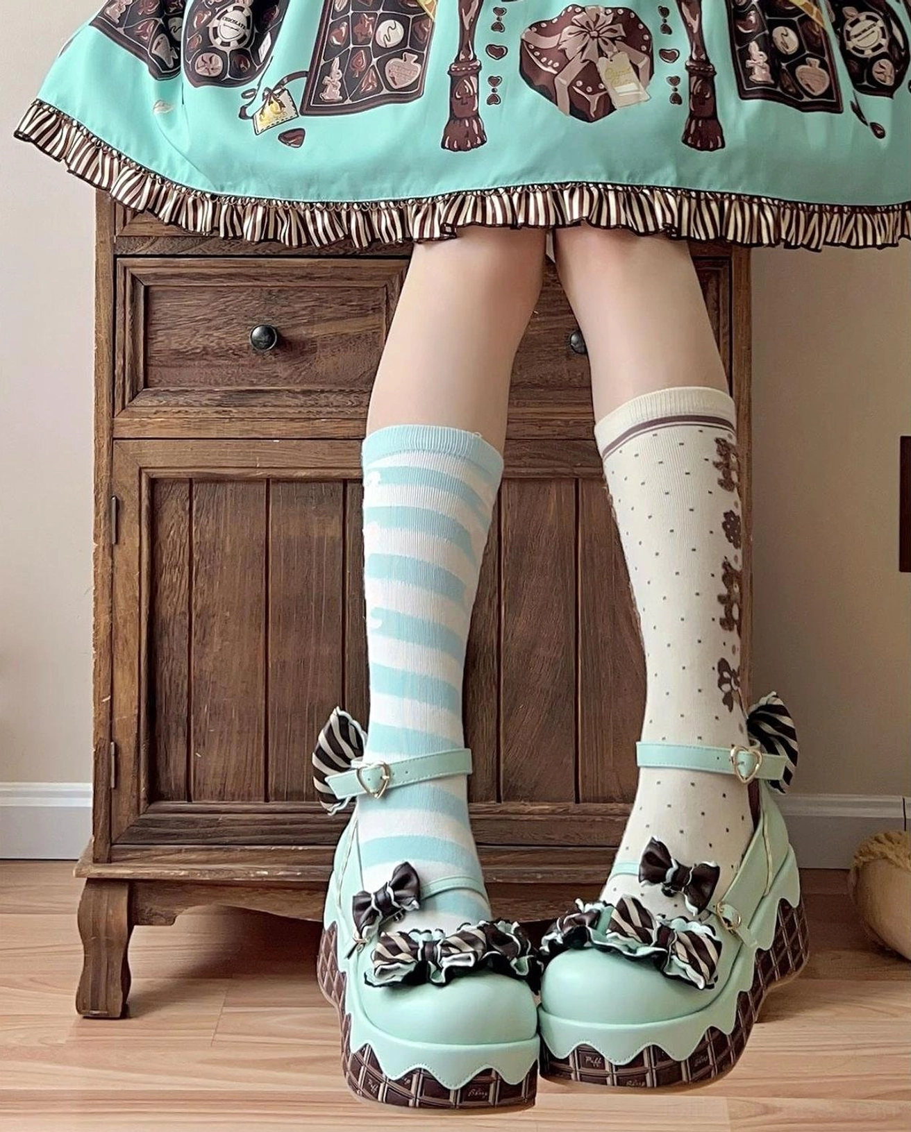 Mint green sweet lolita platform shoes with bowknot decorations and chocolate-striped thick sole worn with striped polka dot knee-high socks vintage backdrop
