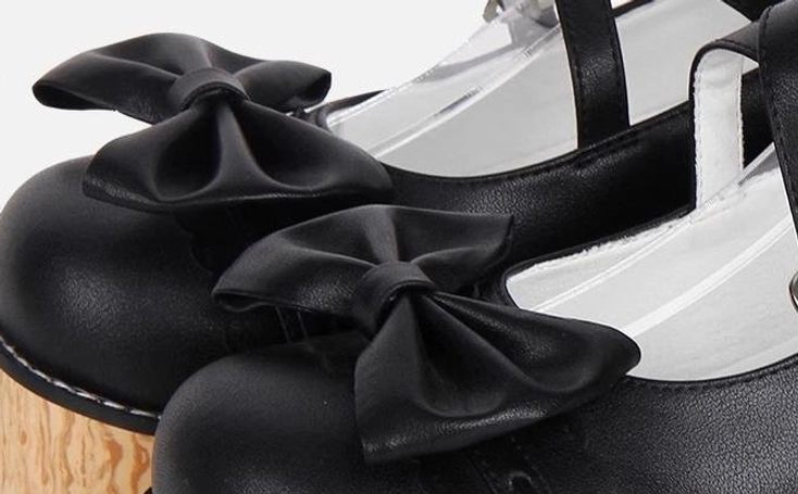 Close-up detail of Princess Lolita shoe vamp showing smooth black microfiber leather, fabric bow decorations on toe cap, and neat precision stitching craftsmanship