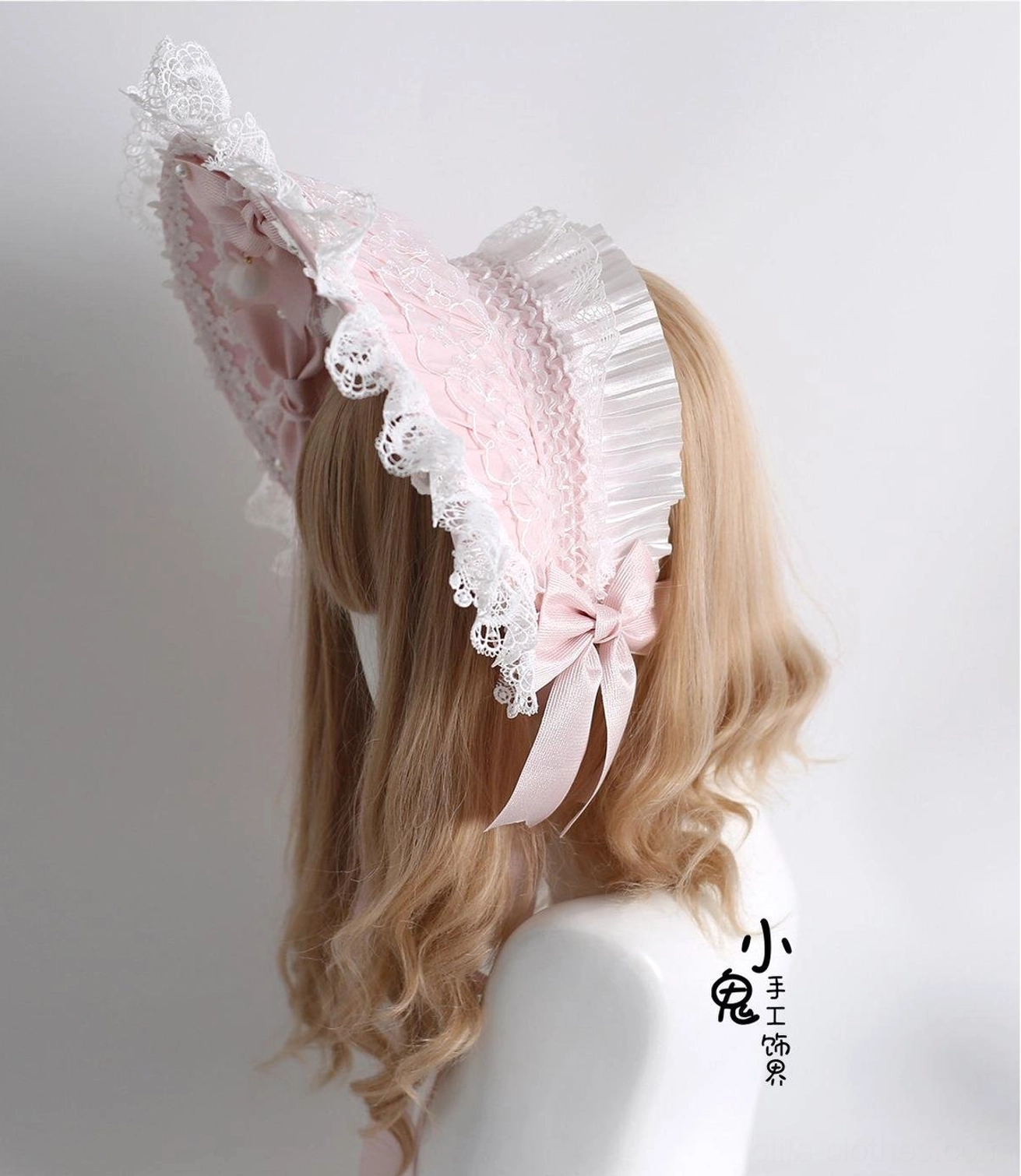 Pointed style Lolita bonnet headdress with elegant curved silhouette, pink satin fabric, white lace ruffled edges, and matching back satin bow on mannequin