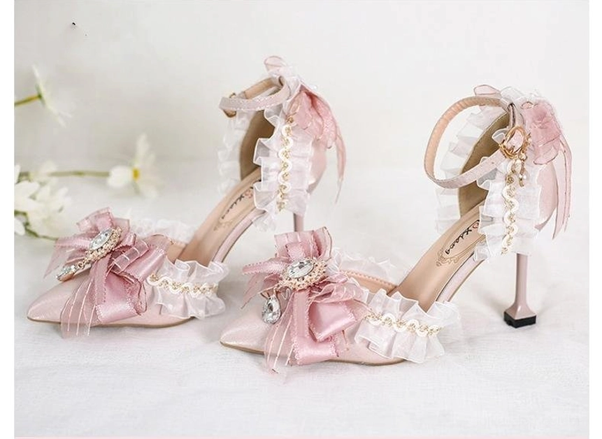 High-angle side view of pink lolita wedding pointed-toe heels with two differently styled decorative bows, delicate stiletto heels, and ruffled ankle straps on floral background