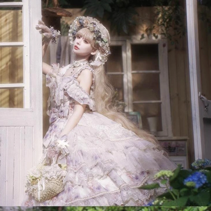 Side profile of lolita chiffon floral dress showing off-shoulder ruffled sleeves and floor-length tiered ball gown silhouette, model leaning on white french window holding flower basket