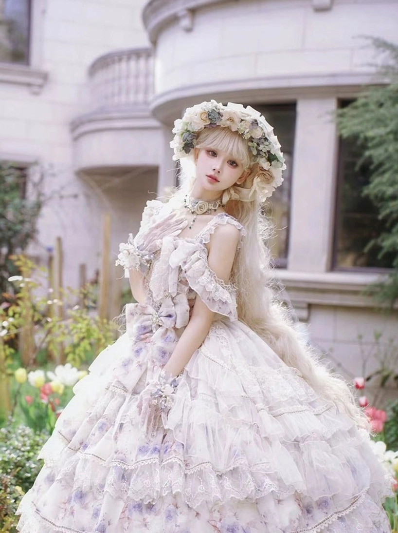 Front full-body portrait of lolita wedding-style princess dress with ruffled off-shoulder neckline, multi-layered tulle ball skirt, all-over floral print, model wearing flower wreath in villa garden