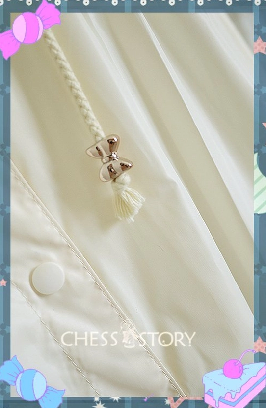 Close-up front fastener and decorative detail cream Lolita raincoat showing bow-shaped metal charm braided tassel round plastic button