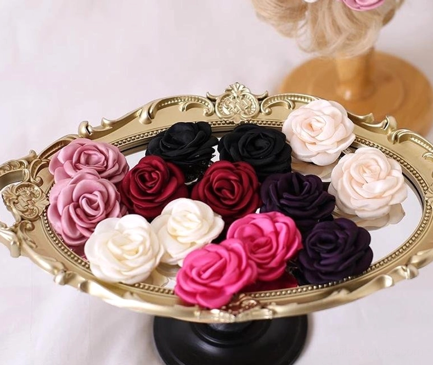 High-angle flat lay of complete fabric rose hair clip set on ornate golden serving tray with neatly arranged mixed-color satin roses