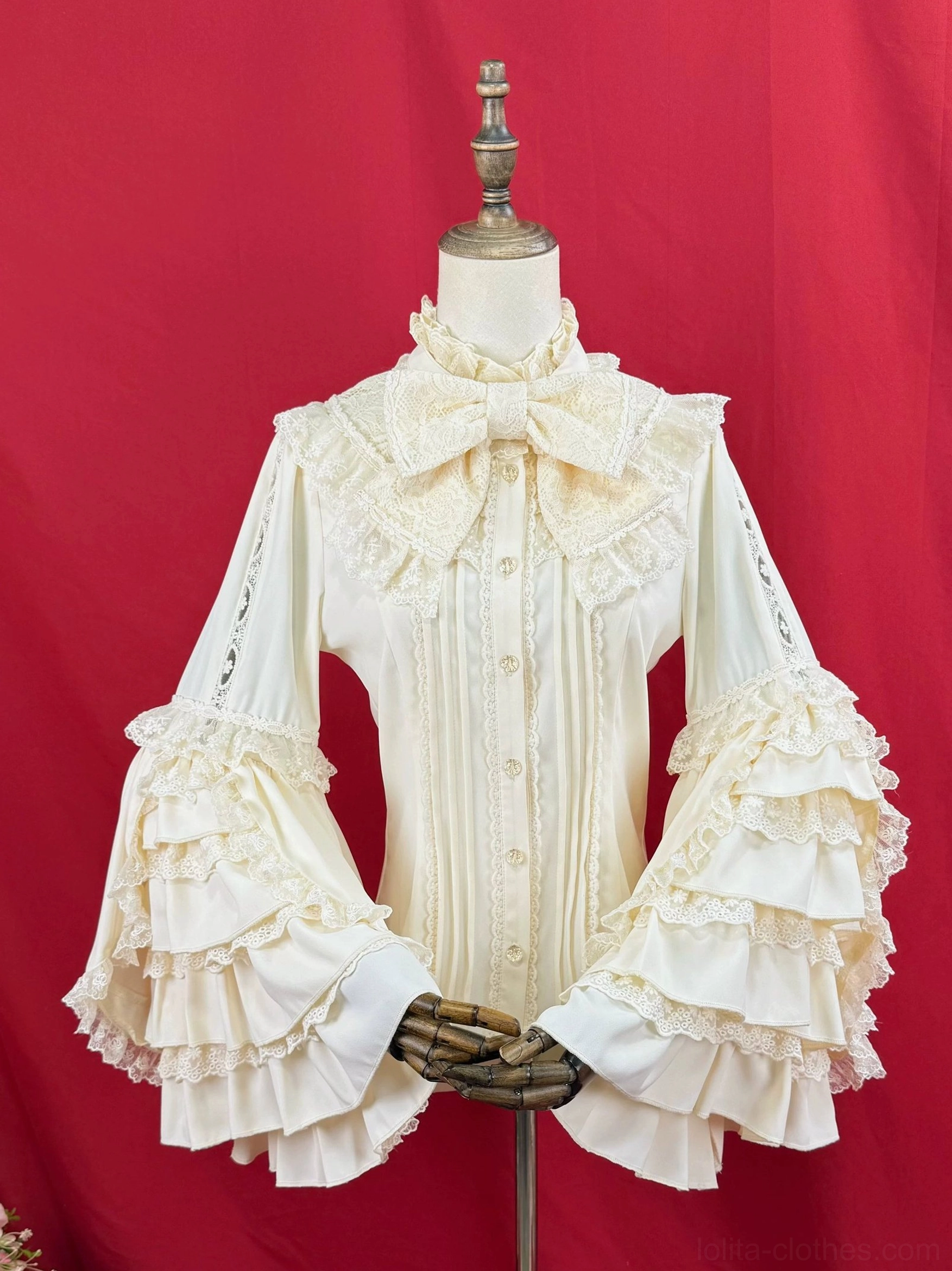 Lolita ruffled sleeve blouse left side front close-up, cream white fabric with wooden hand prop, detailed multi-layered ruffled bell sleeves, bow collar, front lace details
