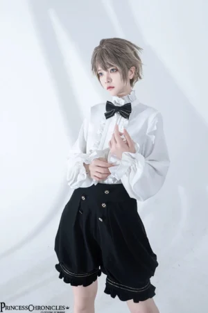 Ruffled white lolita shirt with pleated front, black bow tie, decorative double buttons on high-waisted ruffled black shorts, close-up front styling