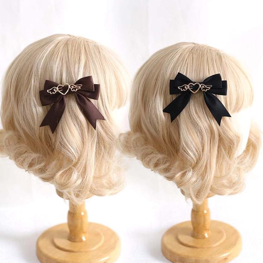 Two lolita bow hair clips displayed on blonde wig mannequin heads in dark brown and black satin with gold decorations