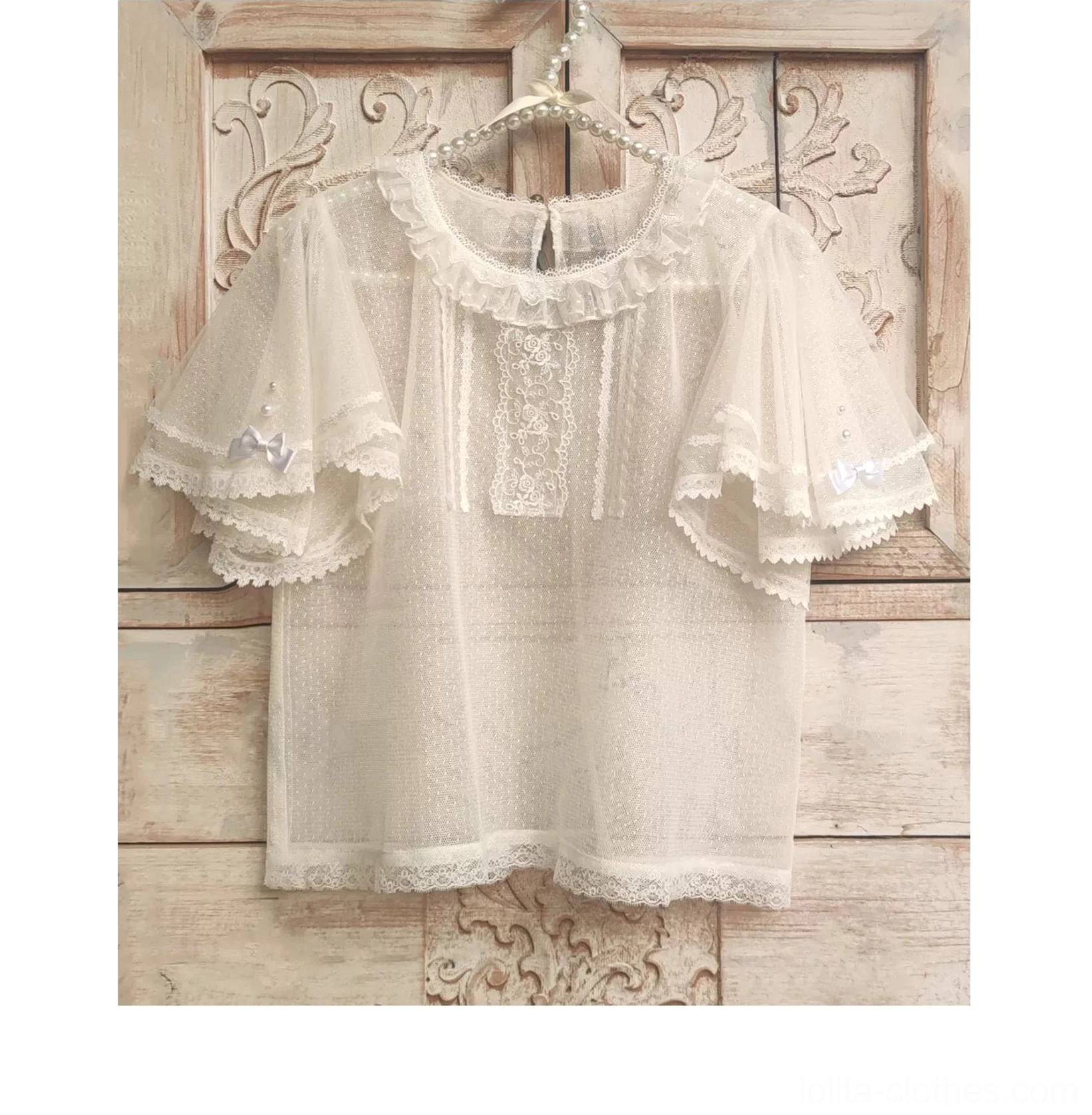 Sheer dot-mesh Lolita tulle short-sleeved blouse with lace yoke neckline and front lace panel hung on vintage wooden door with carved background