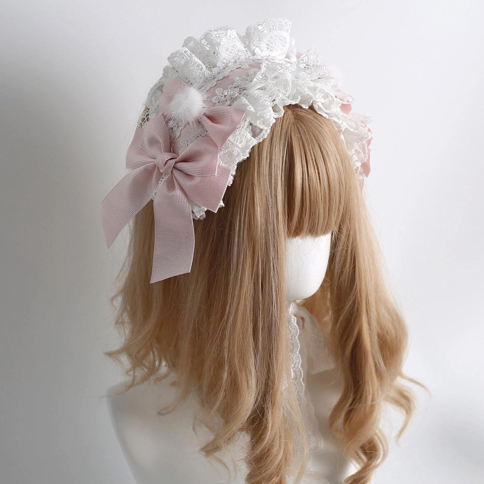 Lolita side head bow accessory with large pink satin bow, white lace frills, fluffy pom-pom, and long decorative lace tail straps, back three-quarter view
