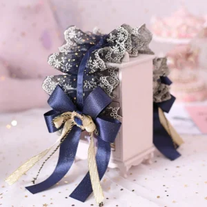 Black gold lace Lolita side headdress with navy blue satin bow and gem ornament, long ribbon tails, pastel pink tabletop styling