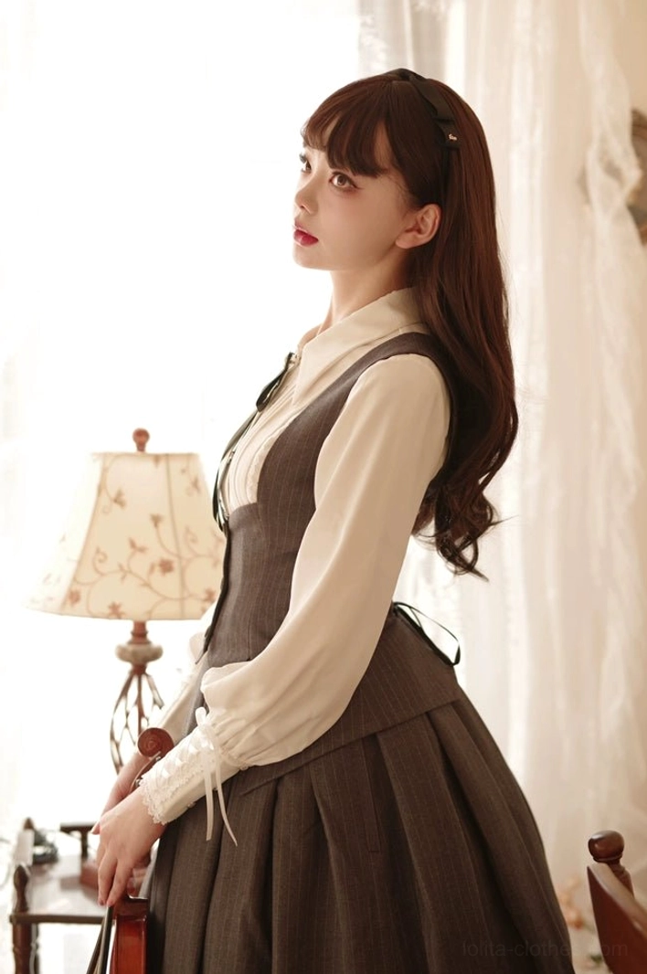 Side-profile daily Lolita coordinate featuring cream long-sleeve pointed collar Lolita shirt with high-waisted brown midi suspender skirt, elegant styling in vintage home studio with table lamp