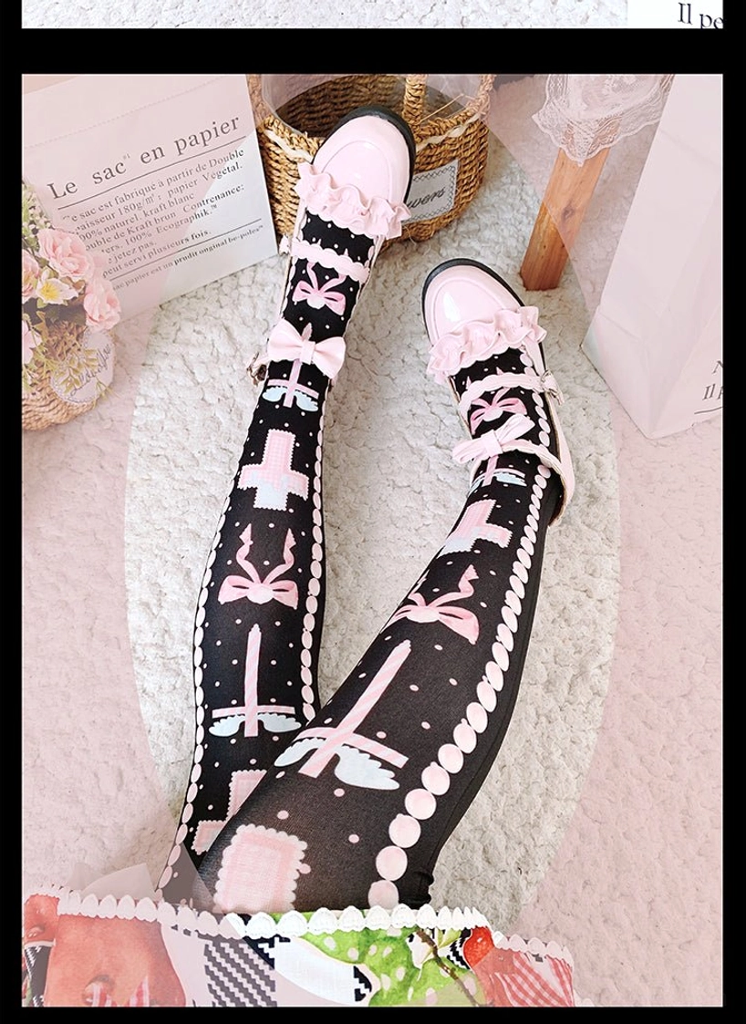 Side angle view of black and pink lolita thigh high stockings with cross bow prints, worn with fruit lolita dress and matching shoes