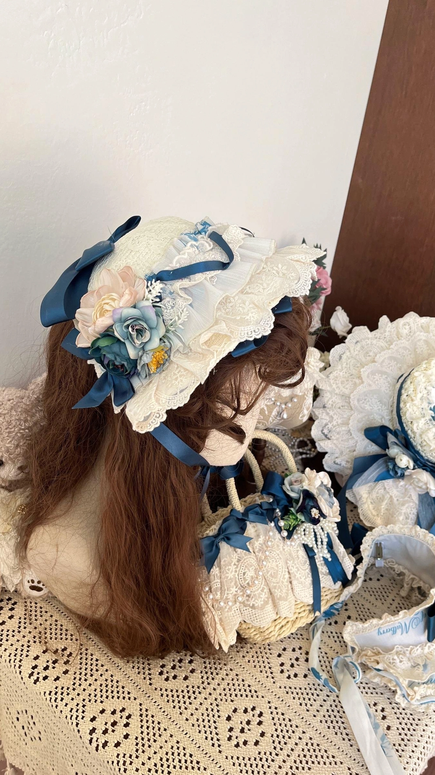 Decorative straw bonnet lolita headdress and matching lace-trimmed handbag displayed on mannequin head with satin bow and fabric flower ornaments