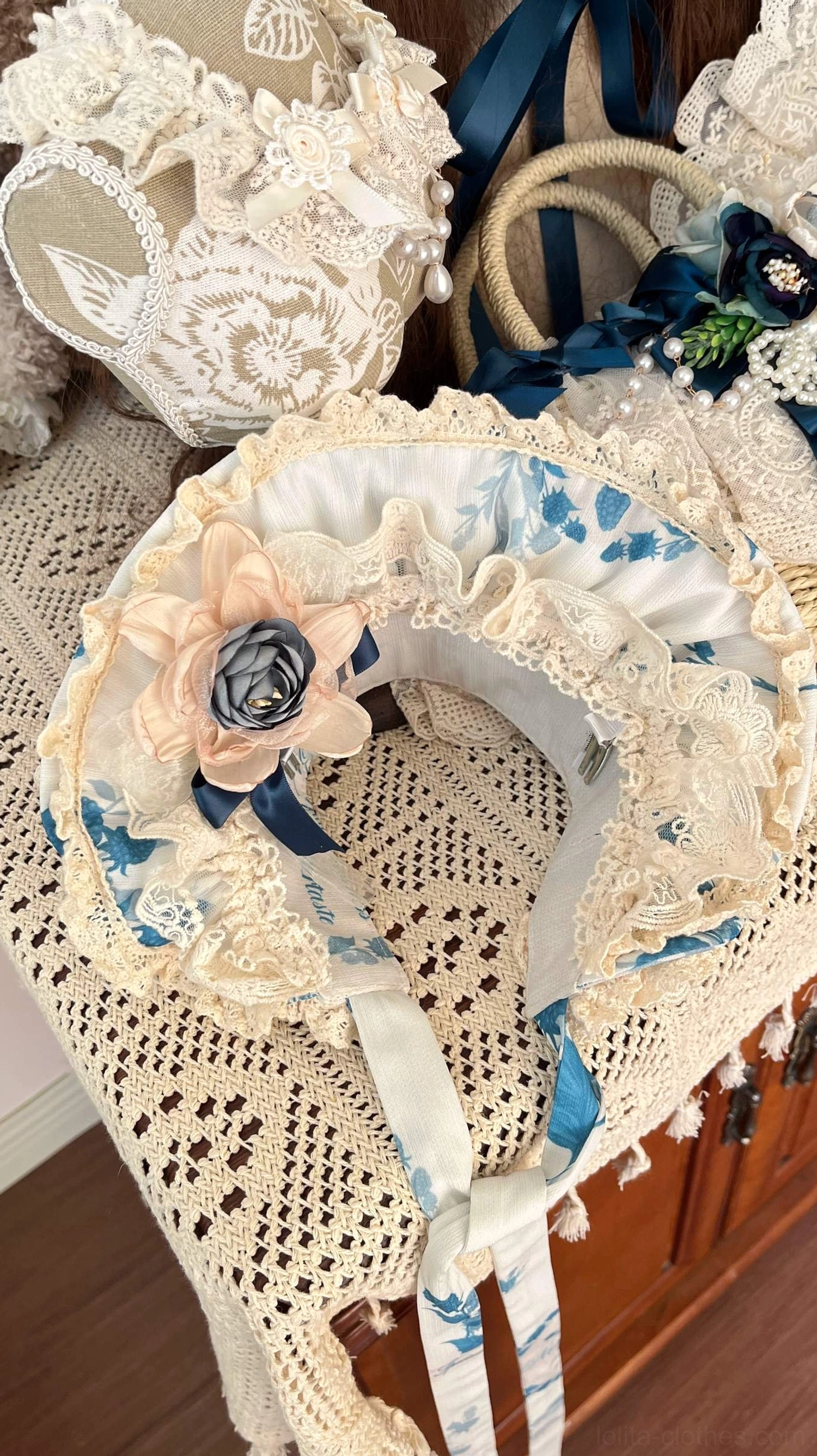 Close-up flat lay of lolita straw bonnet headdress with lace ruffle trim fabric flower decoration and matching handbag accessories on lace tabletop