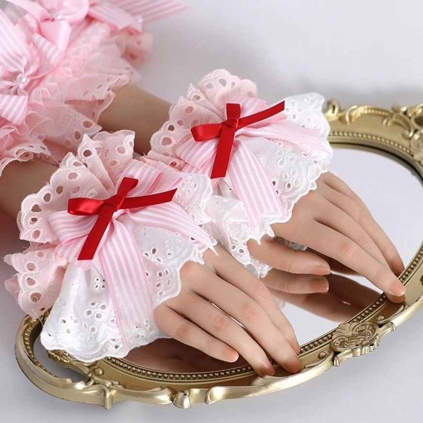 Lolita strawberry lace wrist cuffs pair displayed on hands over vintage gold mirror close-up white eyelet lace with red bow striped ribbon