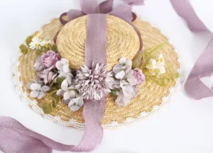 Purple ribbon lolita wheat straw sunhat with purple-grey artificial flower clusters and white lace brim trim, flat lay display on white background