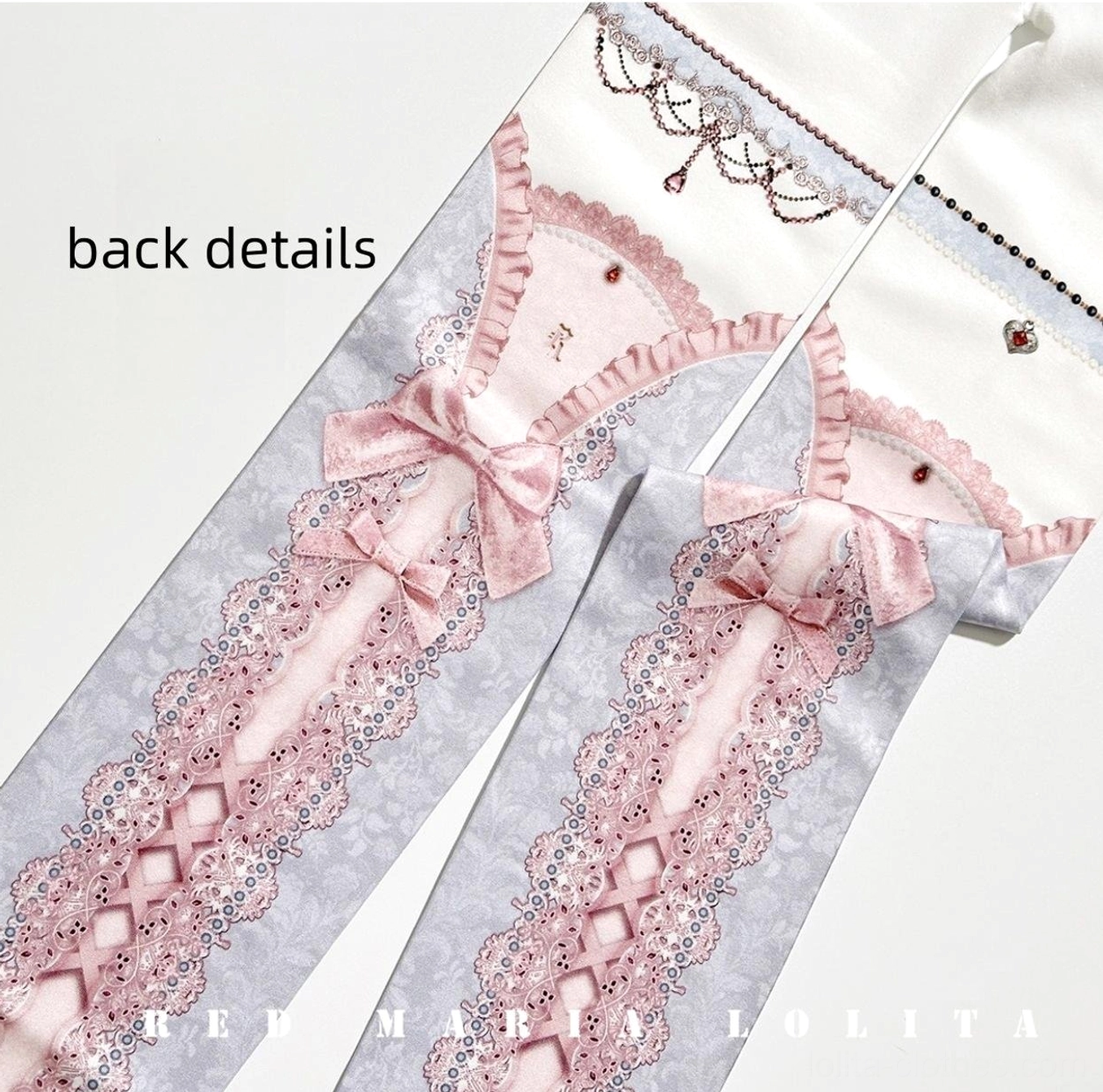 Close-up flat lay detail of digitally printed lolita pantyhose back side featuring lace cross-strap print pattern, bow ornament, and gemstone embellishment on waistband