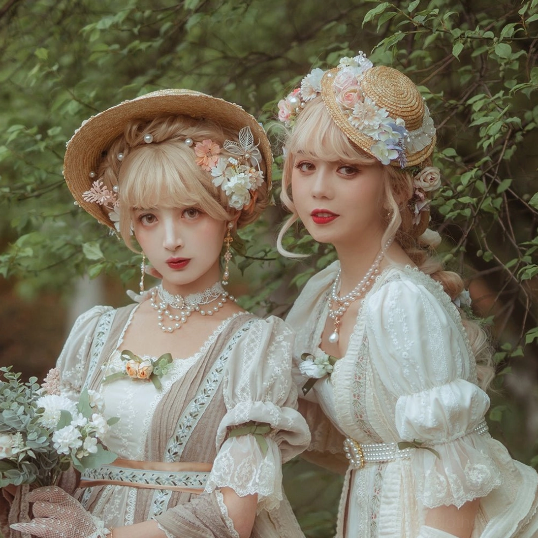 Lolita vintage portrait styling with models in cream lolita dresses straw hats with floral ornaments and pearl chokers in outdoor garden green foliage setting