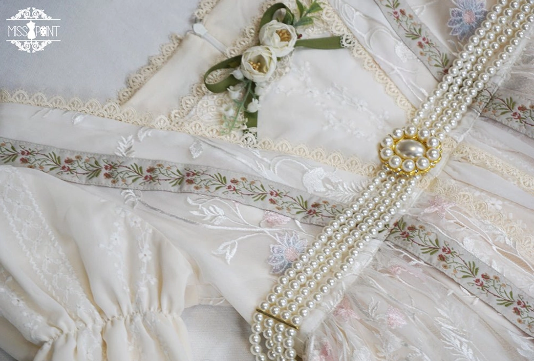 Close-up detail shot of handmade lolita dress waist with pearl beaded chain, gold pearl center buckle and floral embroidery trims
