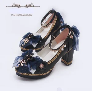 Overhead angled view of lolita thick high heels shoes pair showing black upper with gold embroidery navy blue bow metal flower ornaments and block platform heel