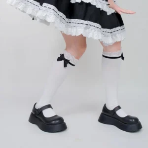 Lolita style white over-the-calf cotton socks with lace cuff and black bow accent side profile leg view