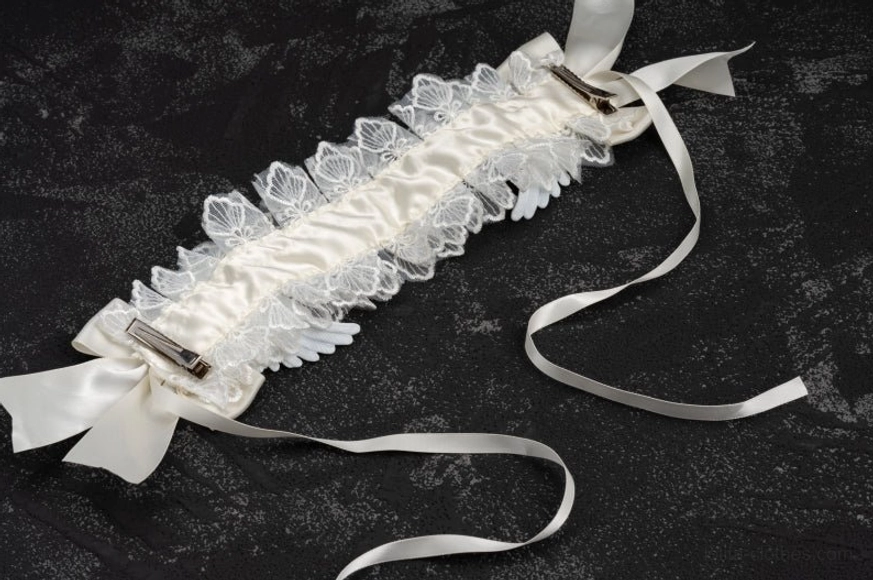 Back view flat lay of white lace gothic lolita angel wings hairband on dark background, showing inner fastening clips and detailed lace trim construction