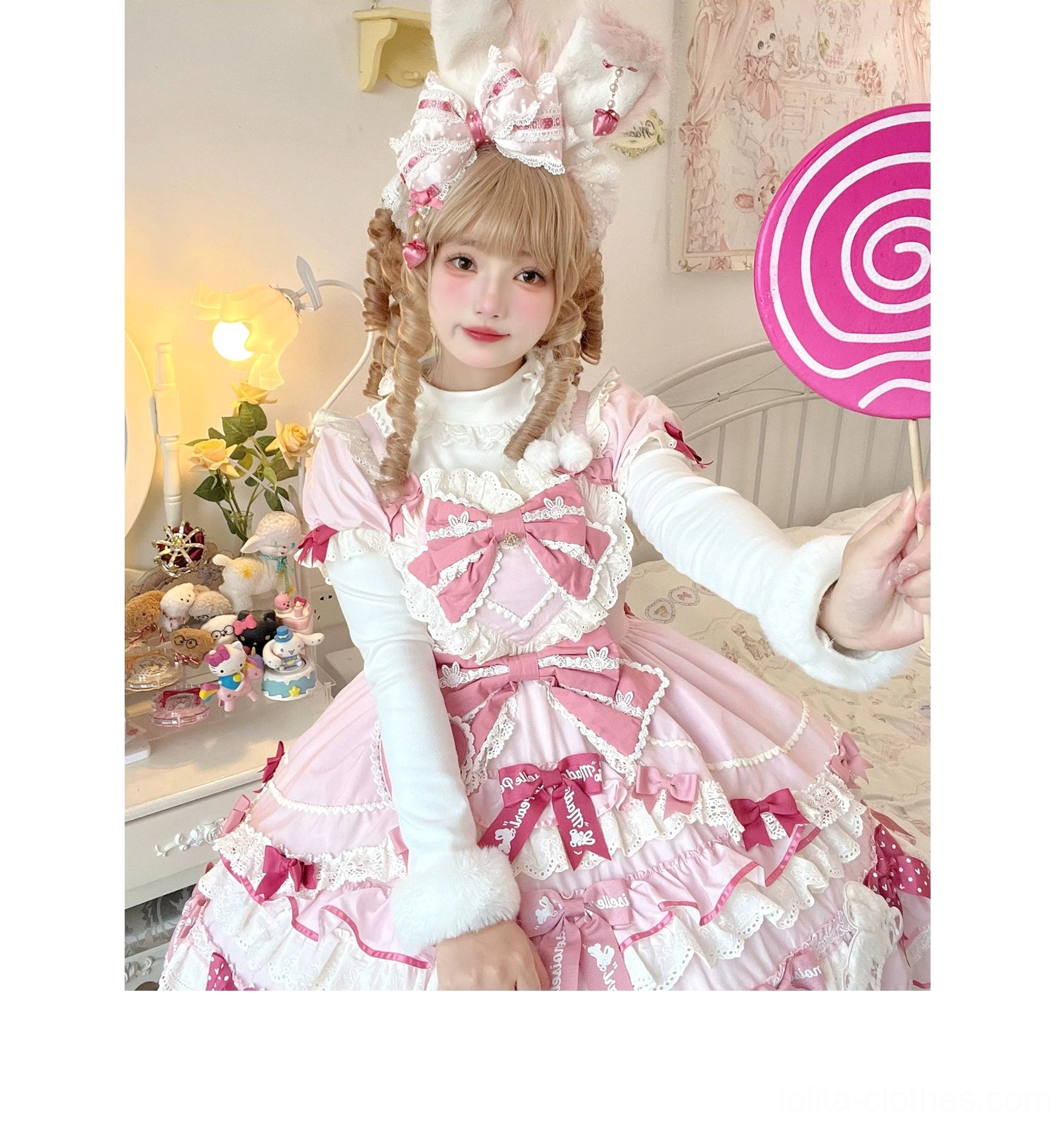 Model wearing sweet pink Lolita dress with white fluffy fur cuff innerwear as layering piece in cozy bedroom-themed photoshoot wearing bunny ear headpiece