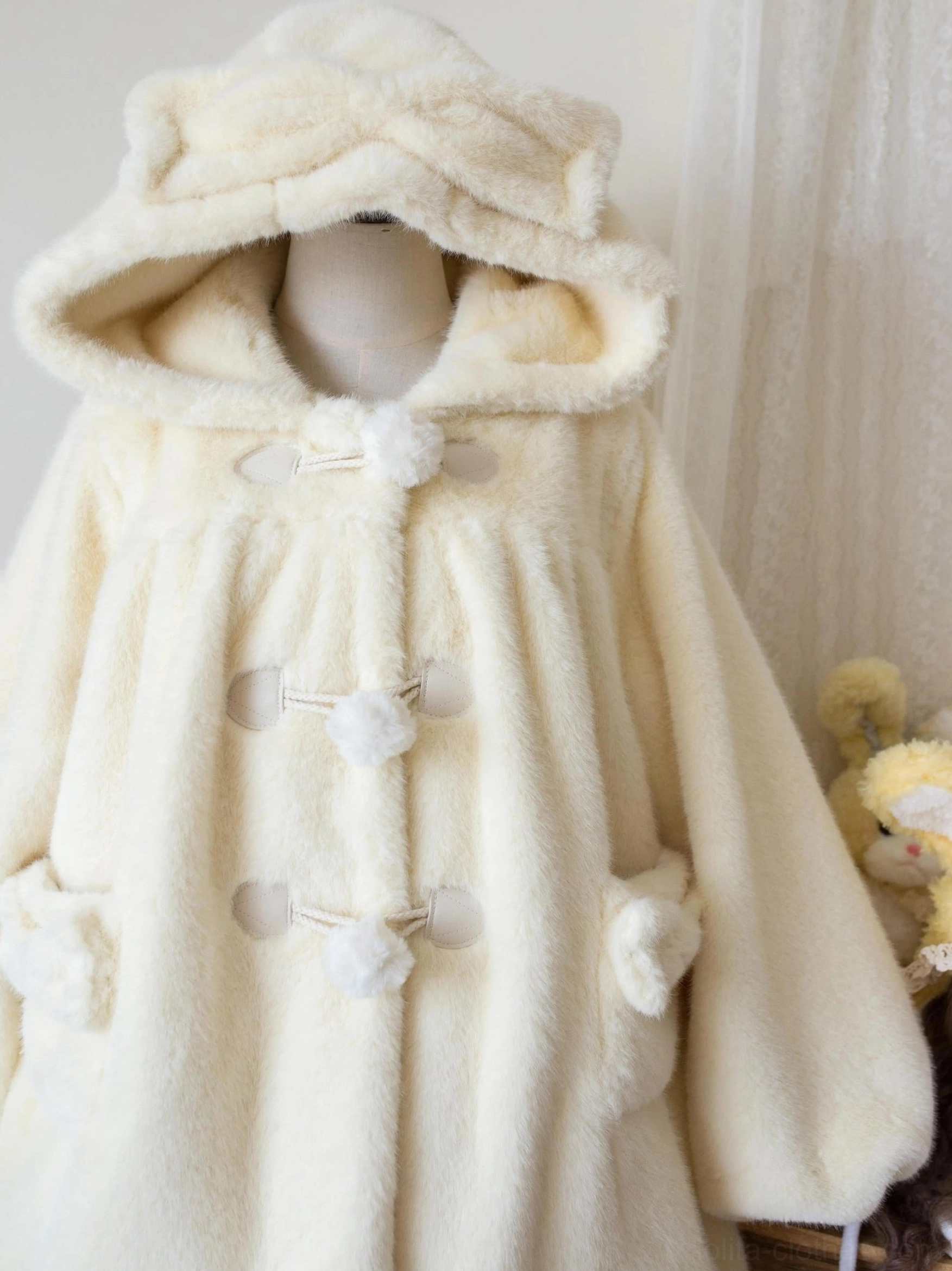 Cream yellow lolita winter thickened fluffy overcoat on single mannequin featuring bear ear hood, pom-pom toggle buttons and soft fleece texture in studio