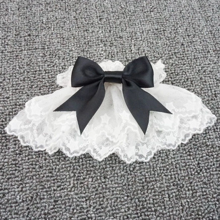 Single lolita wrist cuff with star-patterned lace edging and black satin bow detail close-up flat lay