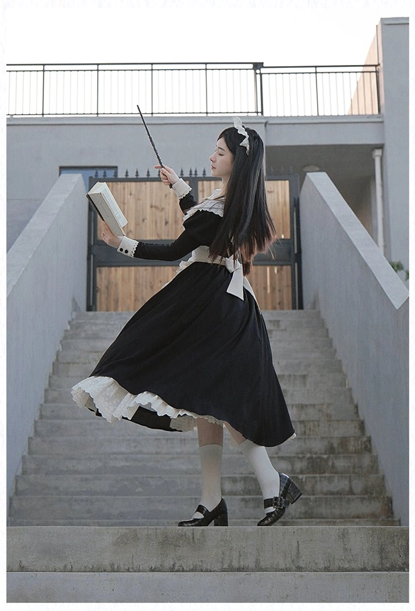 Long maid lolita dress with lace-trimmed skirt worn by model walking upstairs holding book and pointer