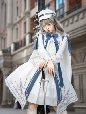Three-quarter front angle shot of military lolita outfit with flowing cape and detachable ribbons, model leaning against European street lamp with sword, showcasing embroidered pleated skirt details