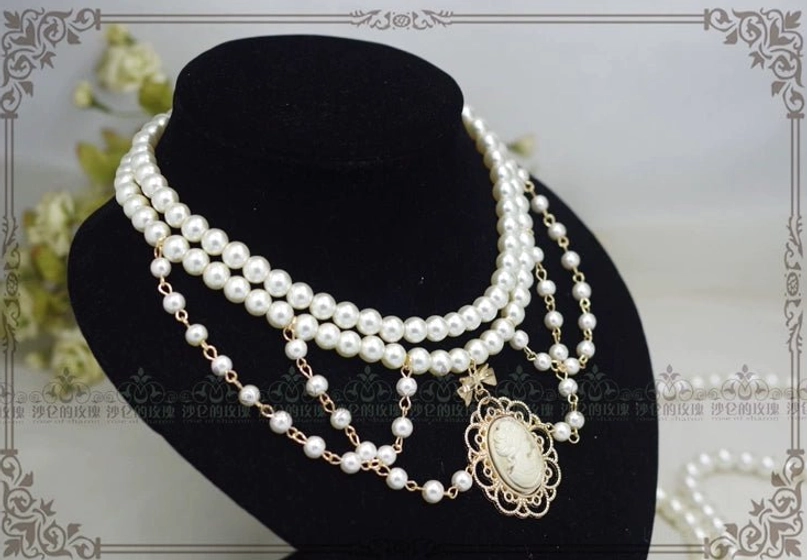 Manor Ball II black pearl cameo necklace detail shot showing golden brown vintage portrait pendant with delicate bow tie frame and multi-layer pearl strands