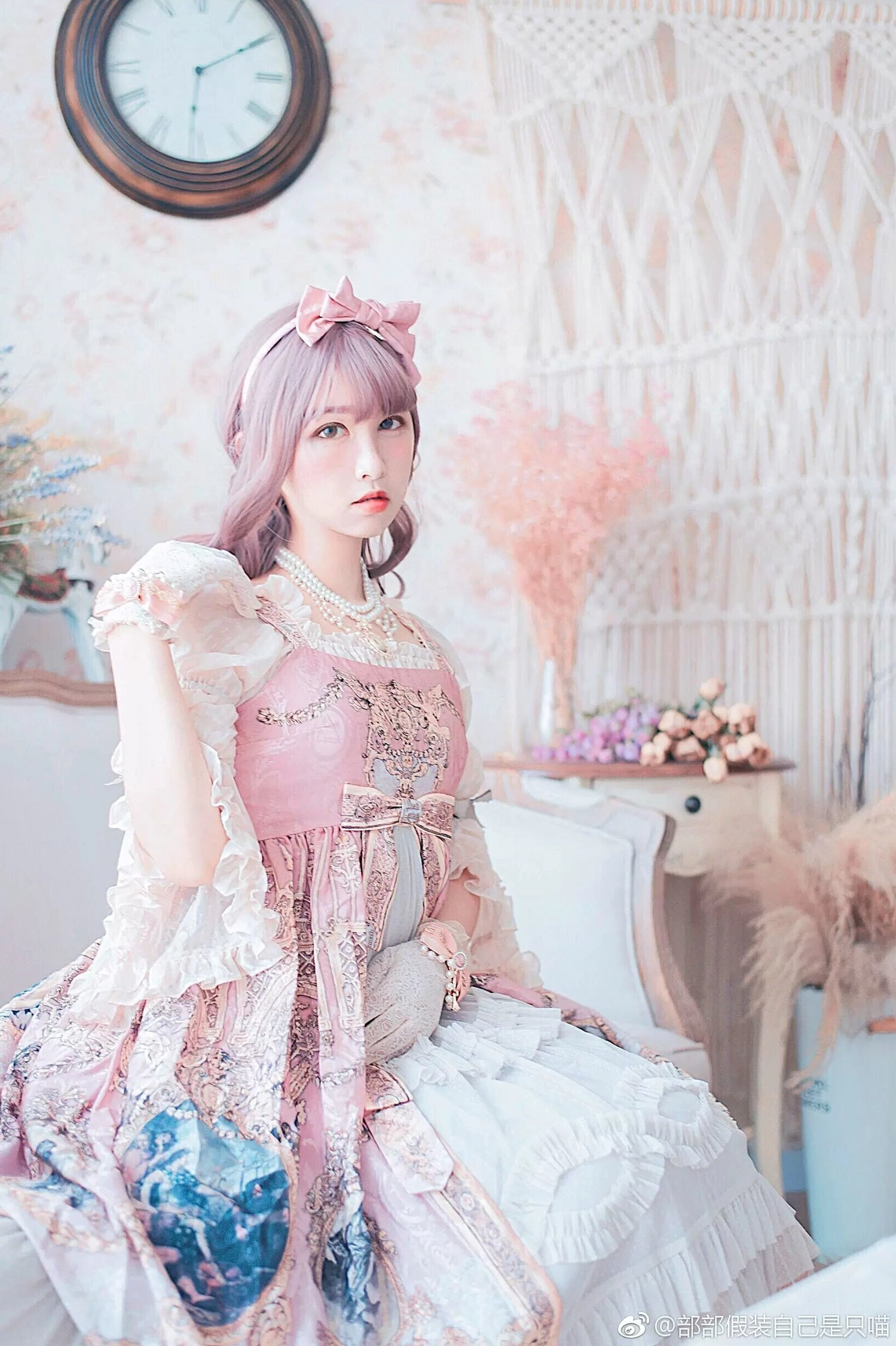 Pink-haired lolita girl in full-body seated portrait wearing floral print pink long dress with Manor Ball II pearl necklace retro European bedroom aesthetic