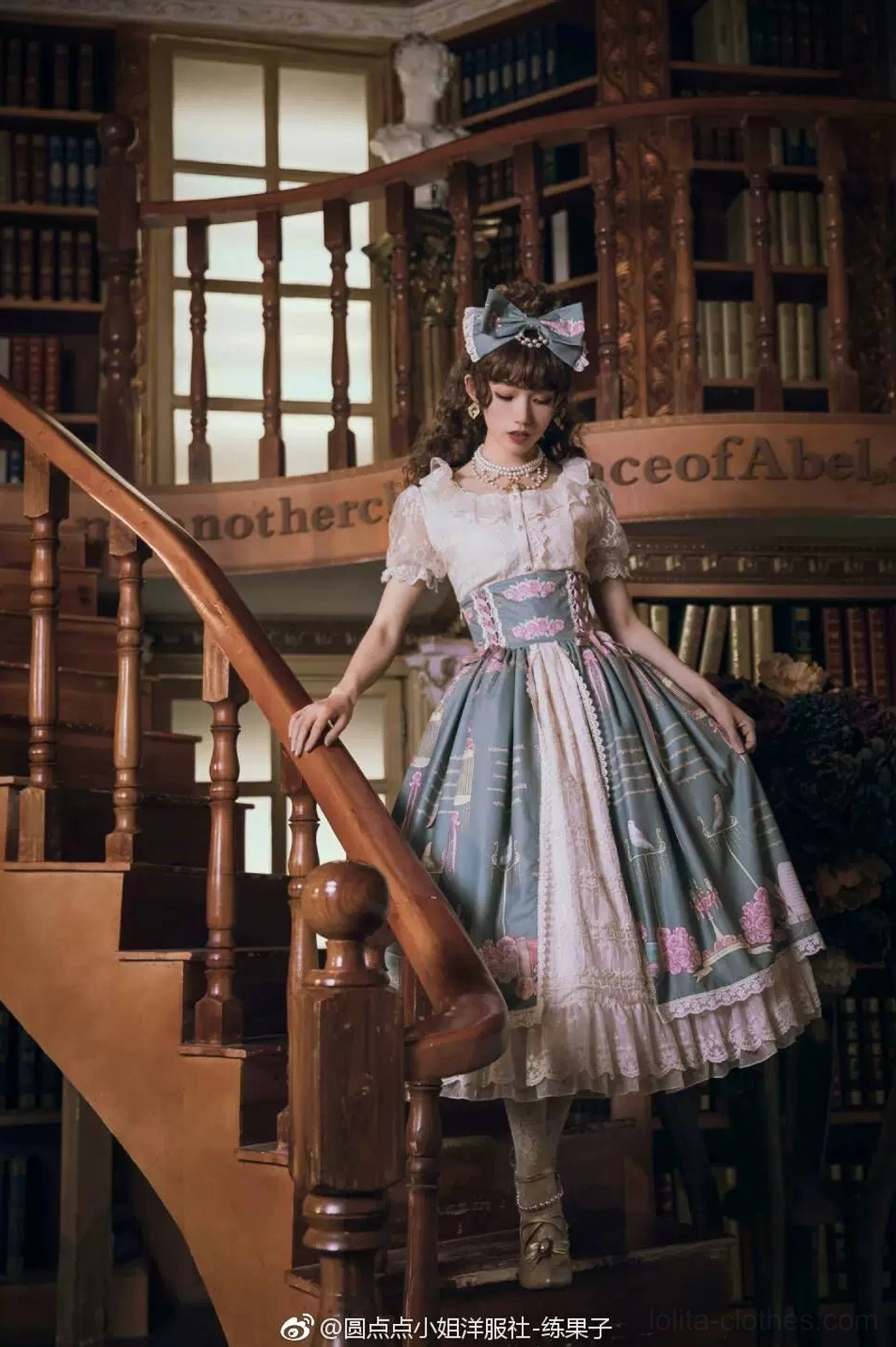 Lolita girl model in half-body side profile wearing blue-pink printed lolita dress with blue bow accessory displaying Manor Ball II cameo pearl necklace vintage study