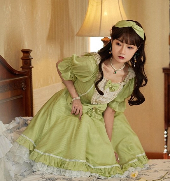 Matcha green classic lolita OP dress with puff sleeves and square neckline lace trim half-body squatting front view vintage bedroom