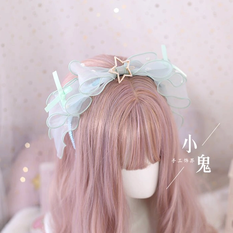 Mint green matcha lolita bow hair clip with layered organza and thin side ribbons close-up three-quarter front view