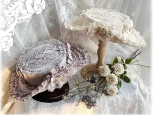 Ivory top hat with matching lace ruffled trims and decorative details, flat lay product photography with fresh flower accents