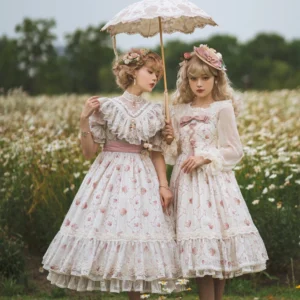 Two models wearing matching vintage rose garden floral sweet lolita OP dresses in cream with pink prints, featuring ruffled collars and layered ruffled skirt hems, posing with vintage lace parasols in daisy field