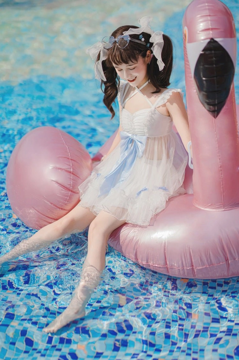 Mermaid lolita swimwear two-piece sitting on flamingo pool float side view sheer dress overlay blue waist bow relaxed poolside