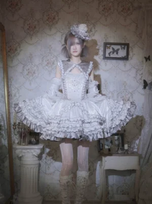 Metallic Angel silver-white punk lolita JSK full front view with rhinestone bodice, multi-layer ruffled skirt, halter neck, long white gloves, and feather hair accessories on vintage bedroom backdrop