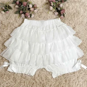 Milk white cotton lolita safety bloomers with tiered ruffle trim and jacquard polka dot texture displayed on faux fur with decorative flowers