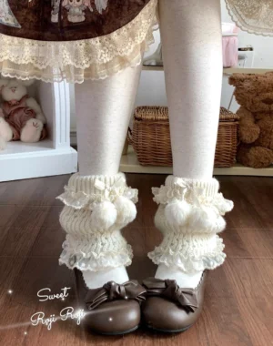 Milky white lolita leg warmers worn on model legs with white opaque tights and brown bow loafers, showing fuzzy pom-pom details and ruffled lace cuffs